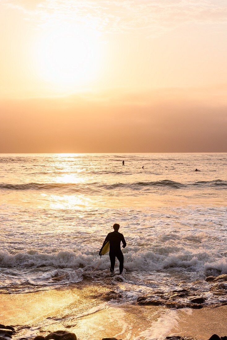 A surfer on the beach in Swakopmund, Namibia at sunset