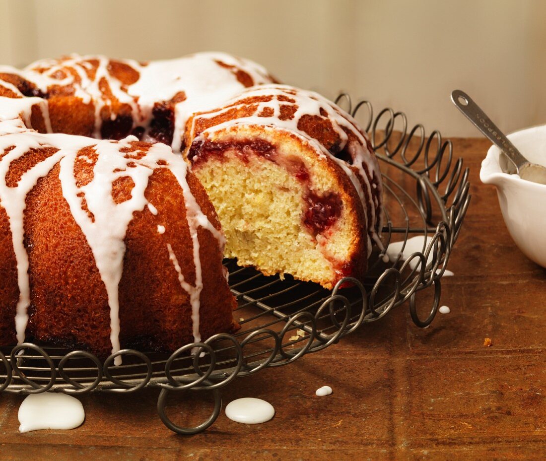 A Bundt cake with raspberries and icing sugar, sliced