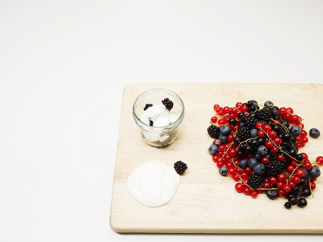 Frische Beeren auf Holzbrettchen und Joghurt mit Brombeeren