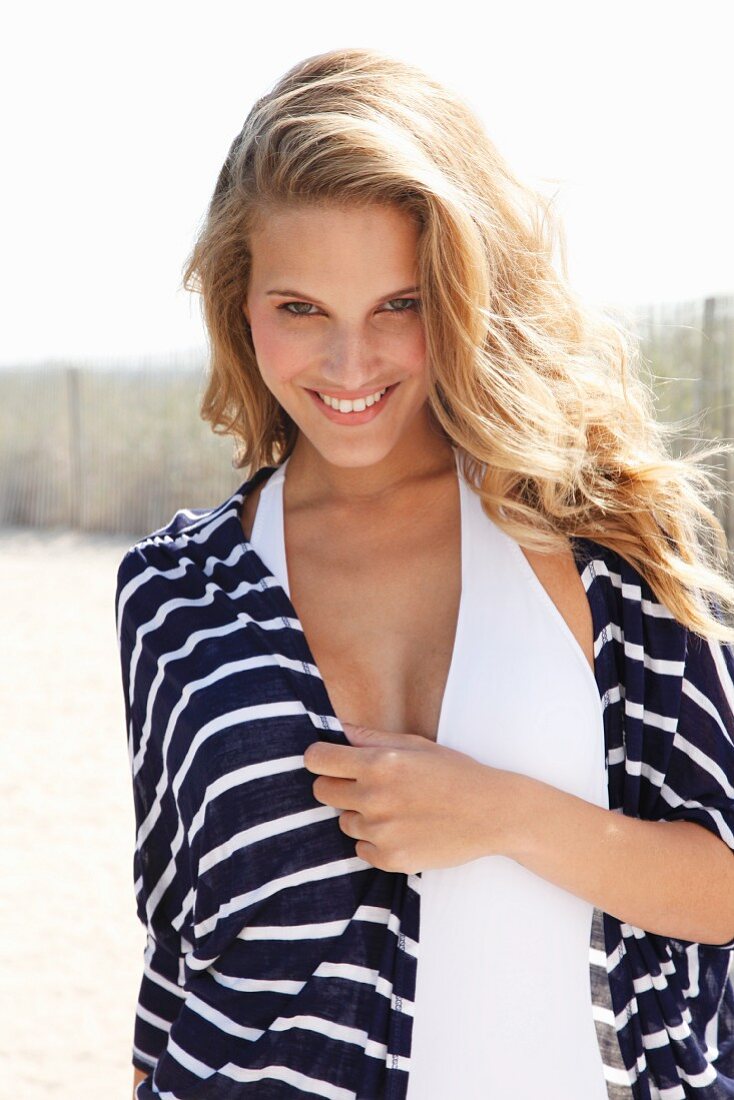 A young blonde woman wearing a blue-and-white stripped jacket over a swim suit