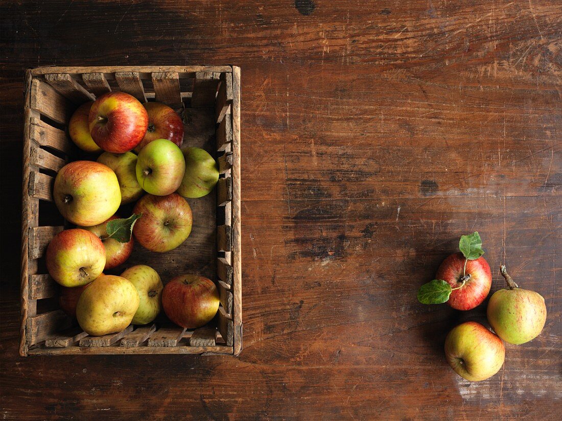 Fresh organic apples in a wooden crate on a wooden surface