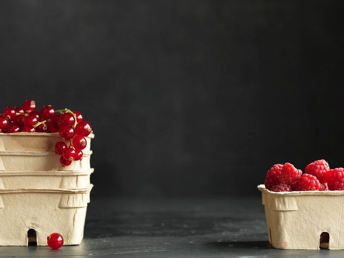 Fresh redcurrants and raspberries in cardboard punnets