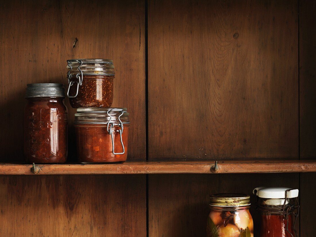 Various preserving jars on a wooden shelf