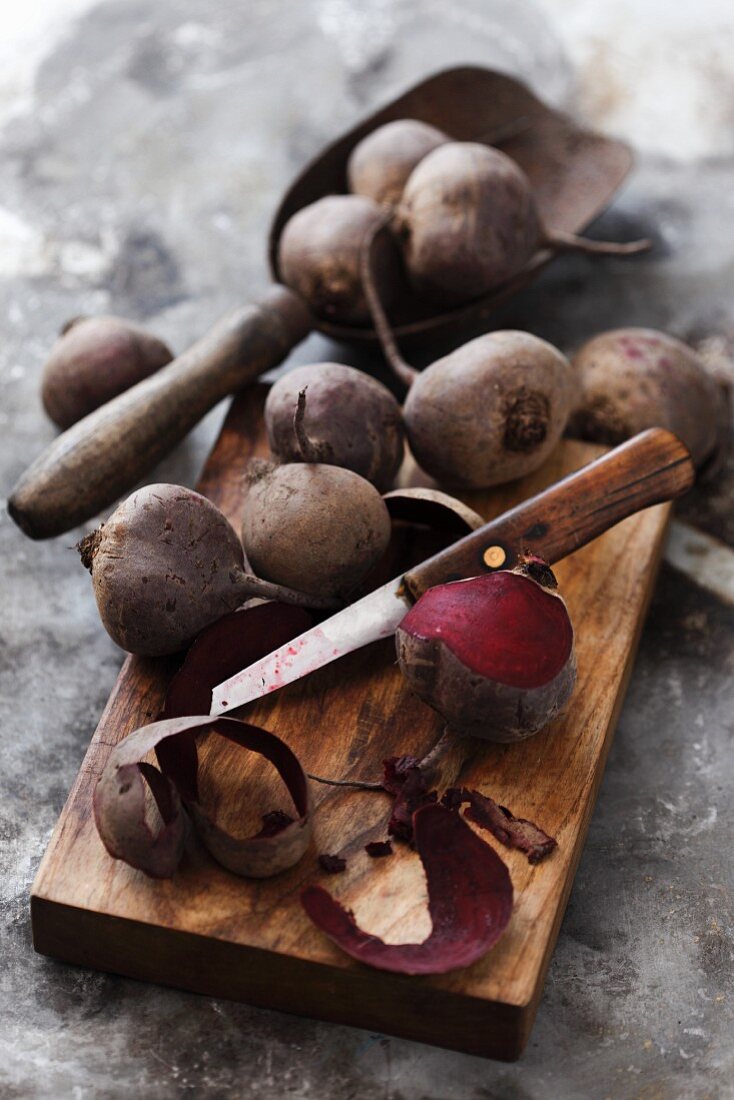 Cooked beetroots on a chopping board, one partially peeled