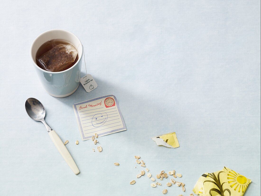 An arrangement featuring a tea cup, a note and scattered oats