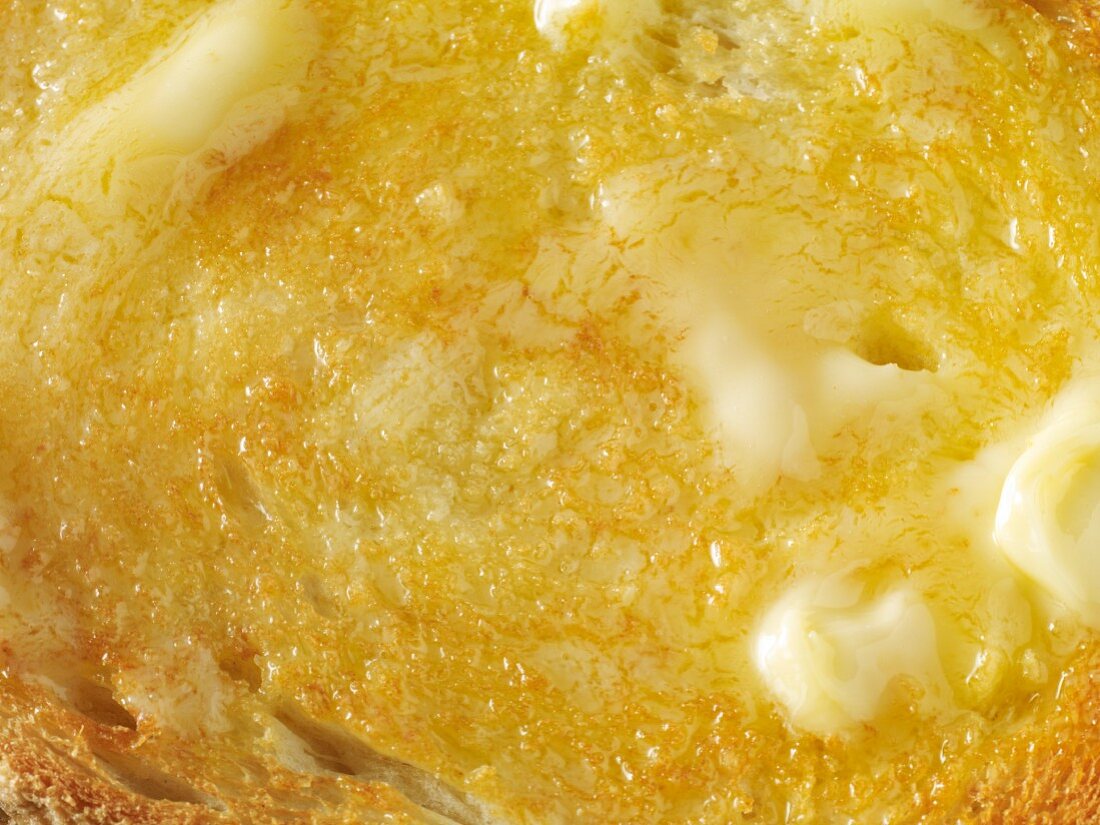 A close-up of a slice of toast topped with melting butter