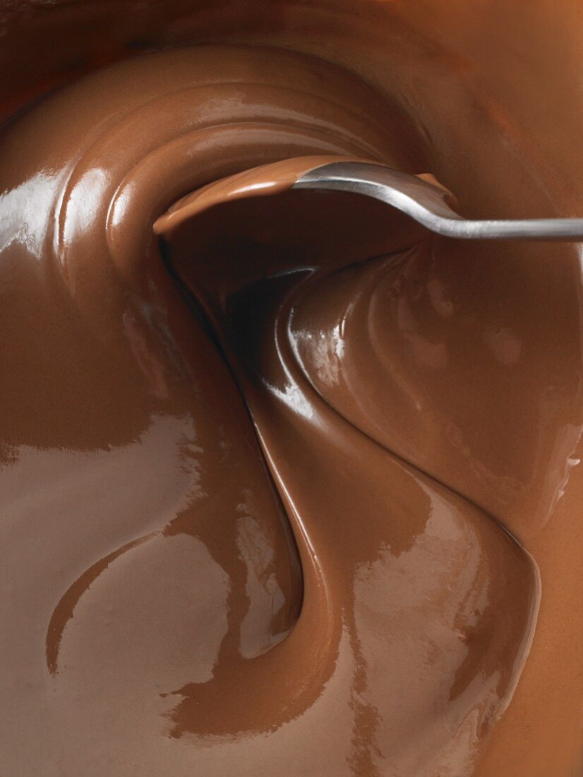 Löffel rührt in geschmolzener Milchschokolade (Close Up)