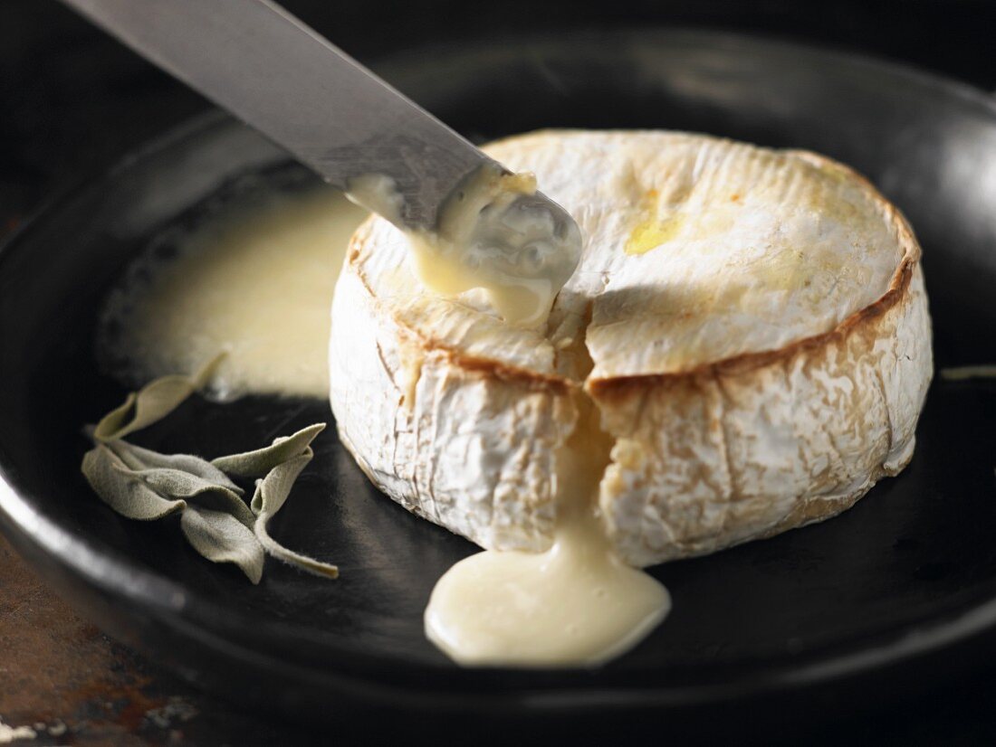 Baked Camembert cheese being cut