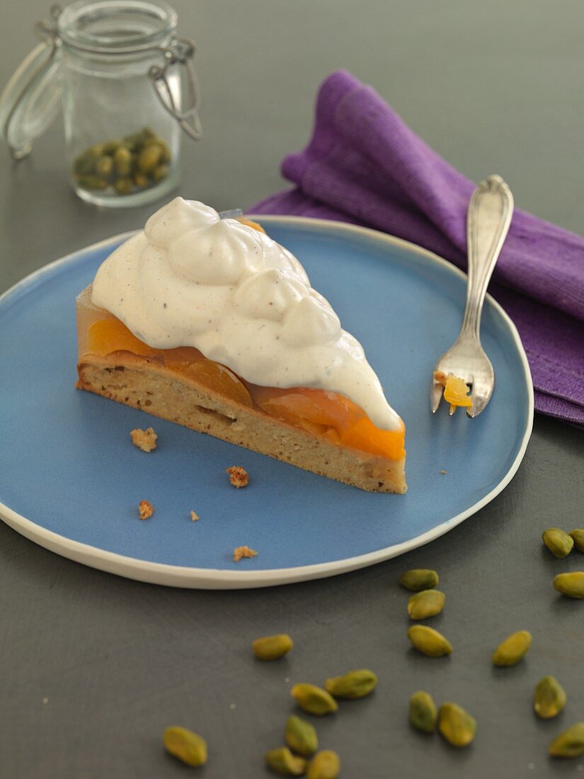 A slice of apricot cake with cream and pistachios