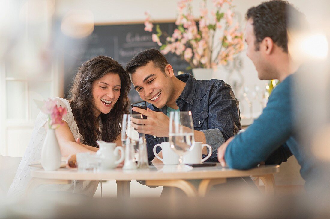 Friends looking at a mobile phone in a cafe
