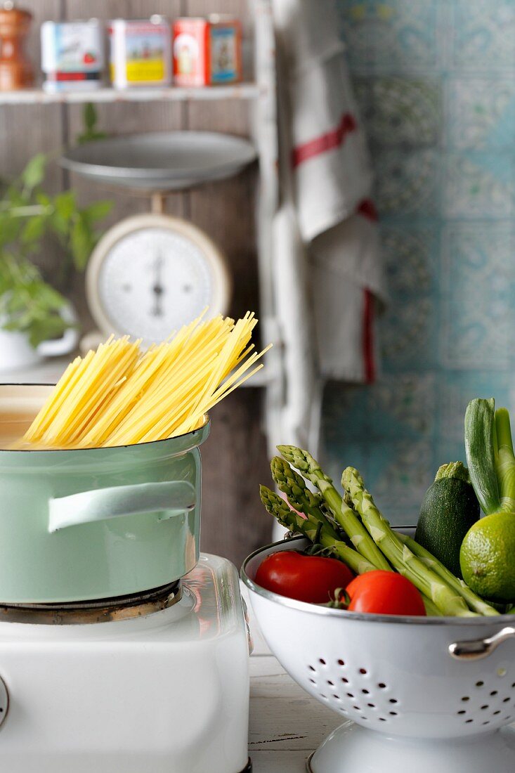 Fresh vegetables in a colander and spaghetti in a pot