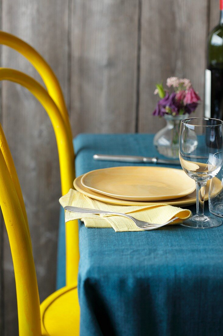 A yellow chair at a laid table