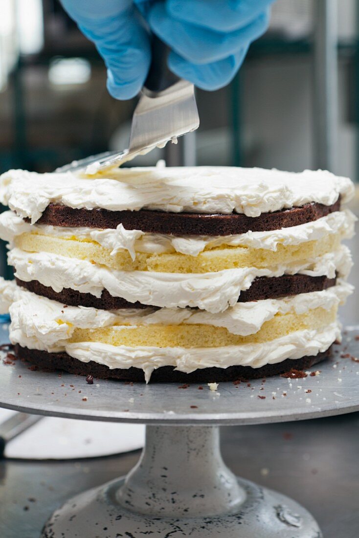 Koch bestreicht Schichttorte mit Frosting