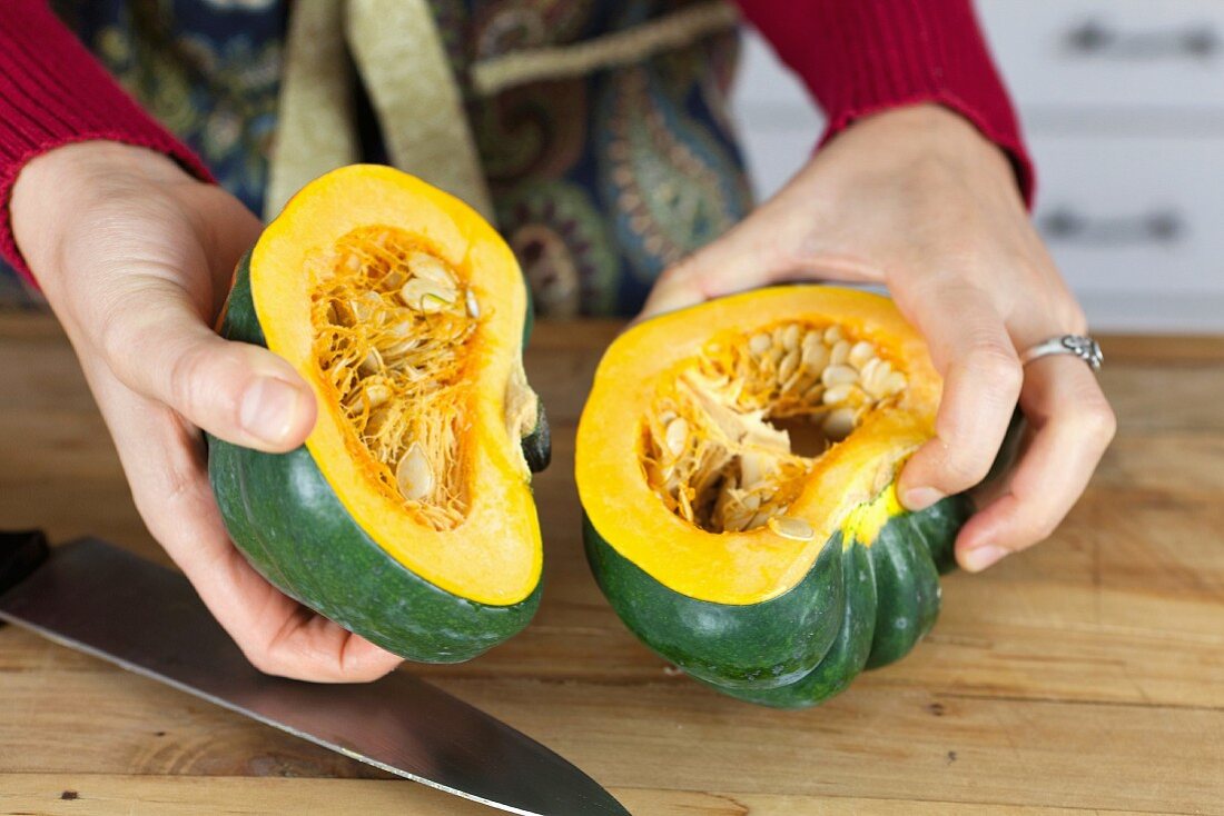A woman holding two halves of acorn squash