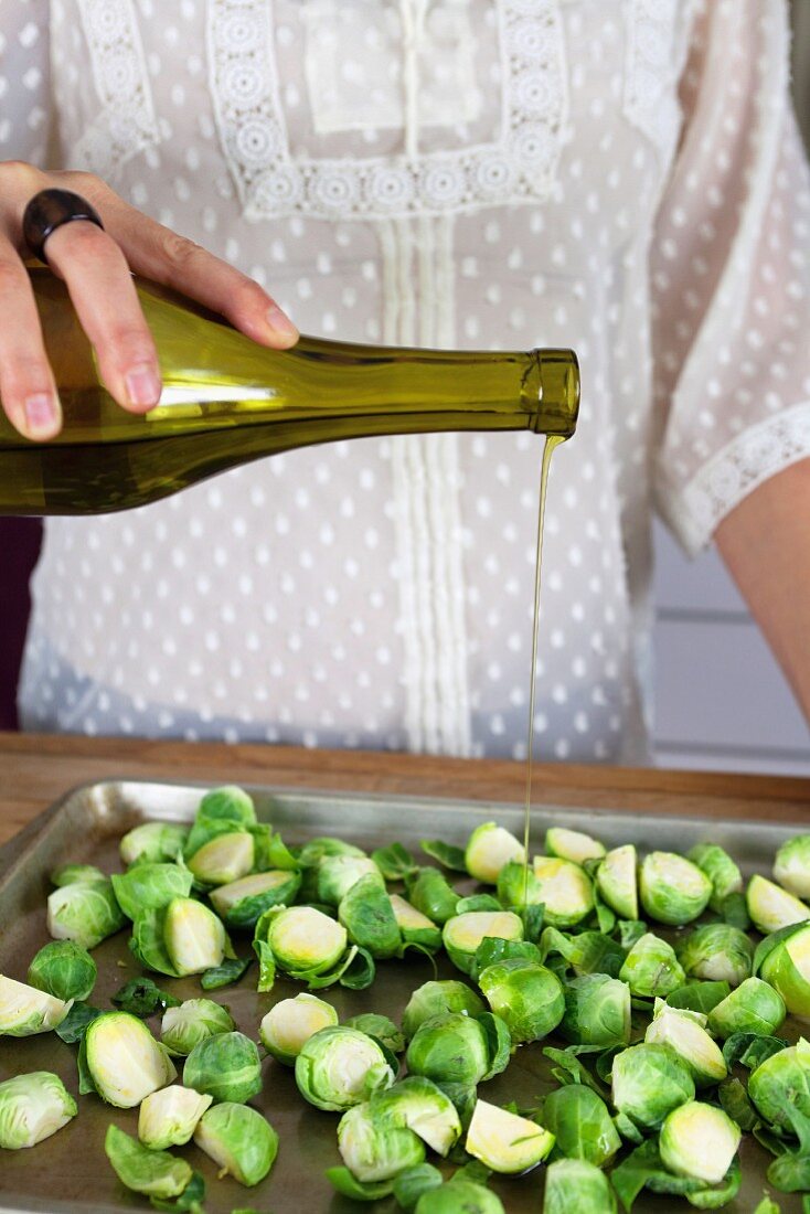 A chef pouring olive oil over Brussels sprouts