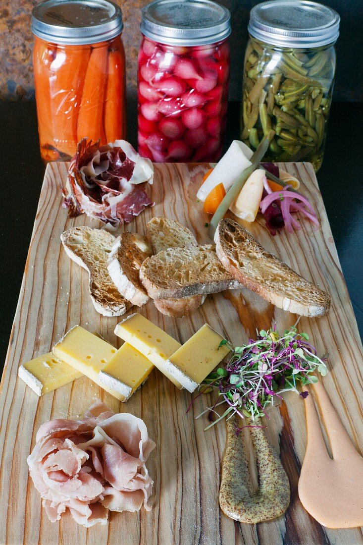 A platter of ham with pickles, crostini, mustard and Manchego cheese