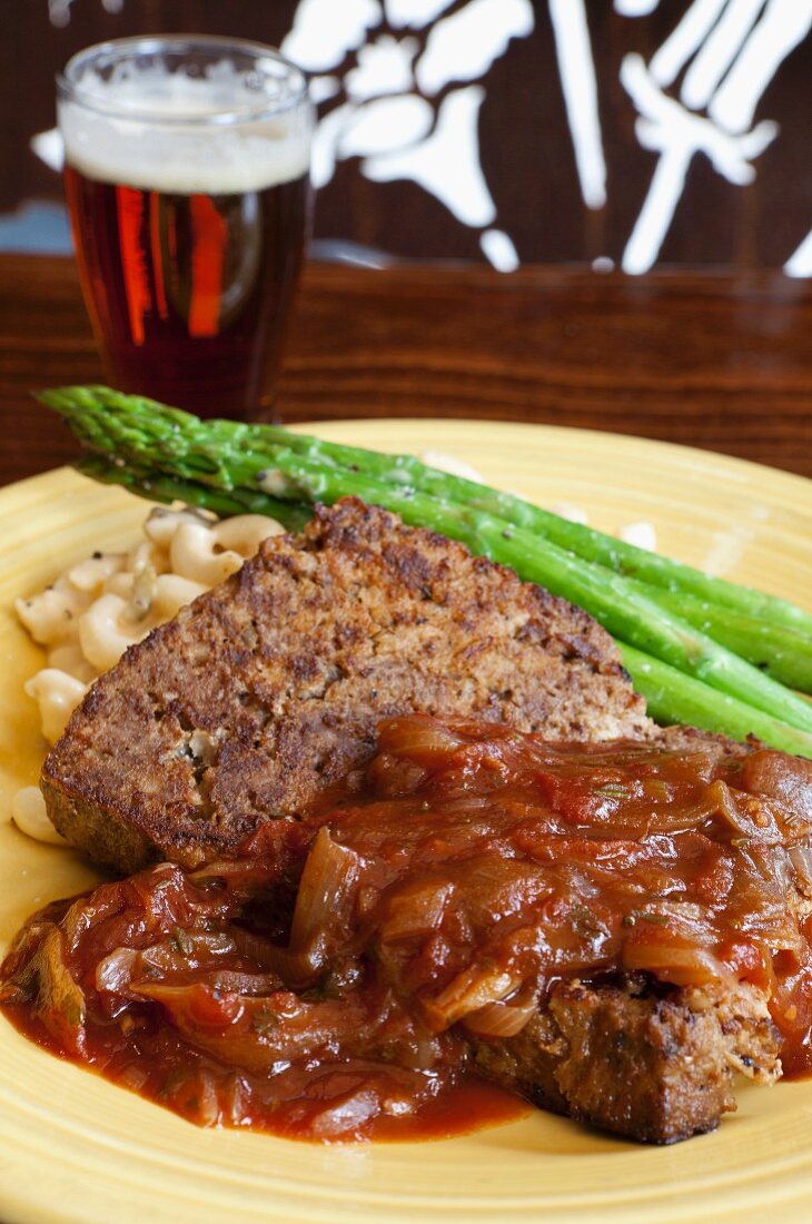 Meatloaf with macaroni and cheese served with asparagus and beer