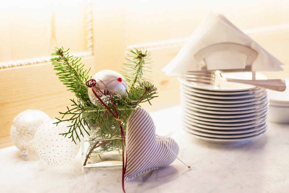 Silberne Weihnachtskugeln mit Tannenzweigen und Stoffherz als Deko für weihnachtliches Buffet