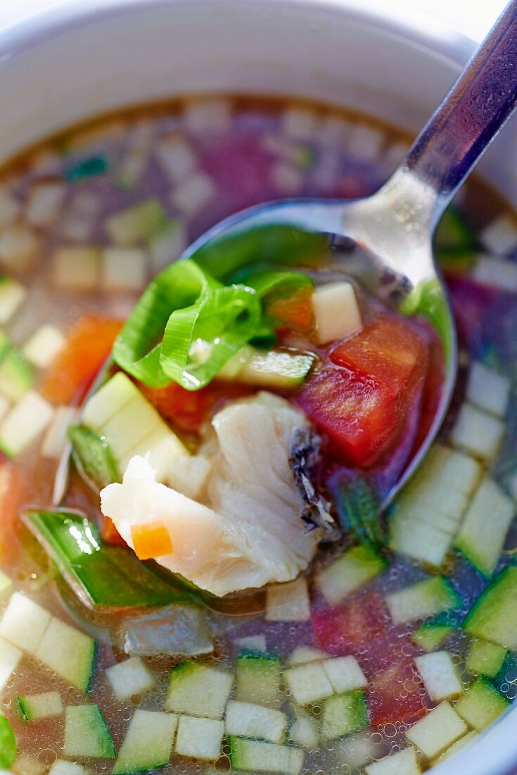 Bouillabaisse auf Löffel in Suppenschale (Close Up)