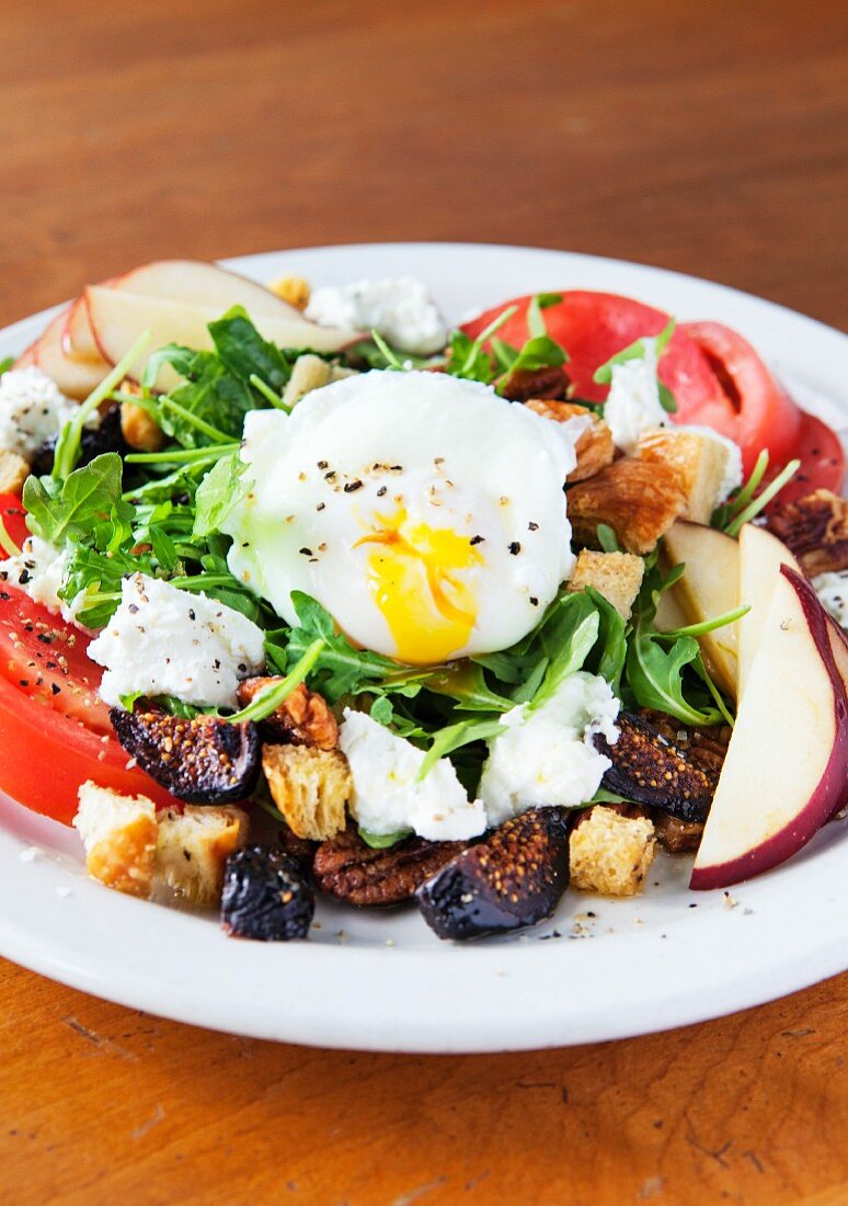 Rocket salad with a poached egg, figs, feta cheese, apples and tomatoes