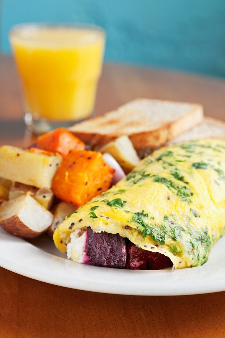 Omelette with beetroot, goat's cheese, parsley, roast potatoes, toast and orange juice