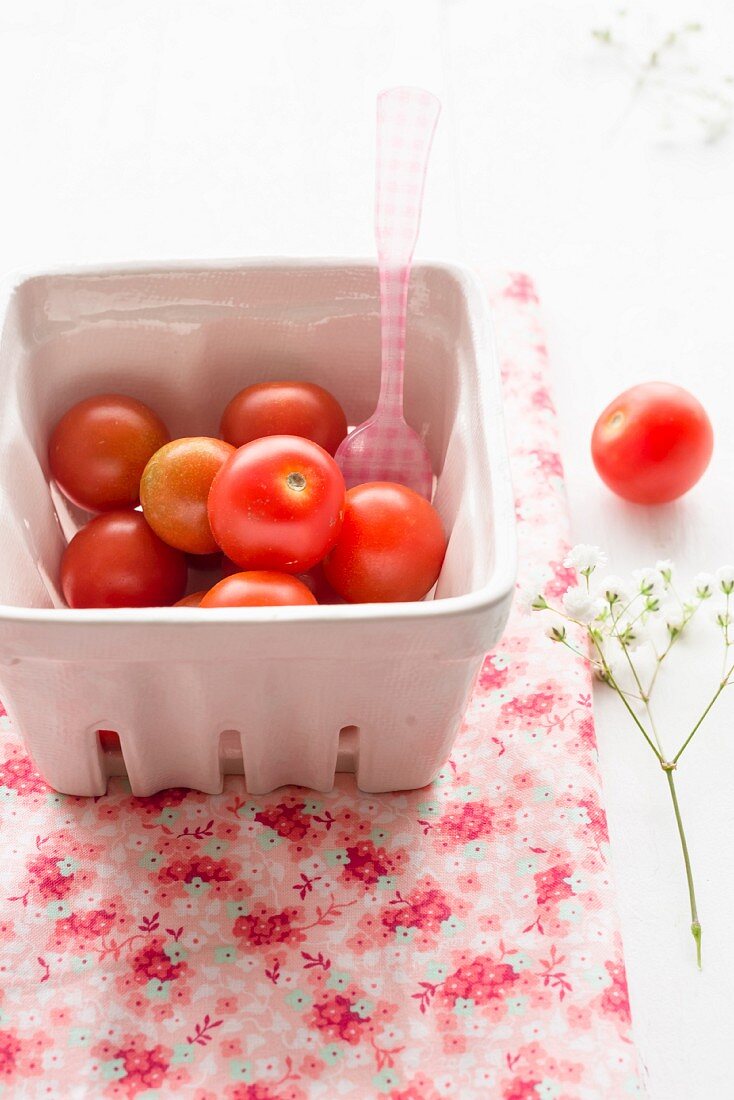 Cherry tomatoes in a cardboard punnet with a plastic fork