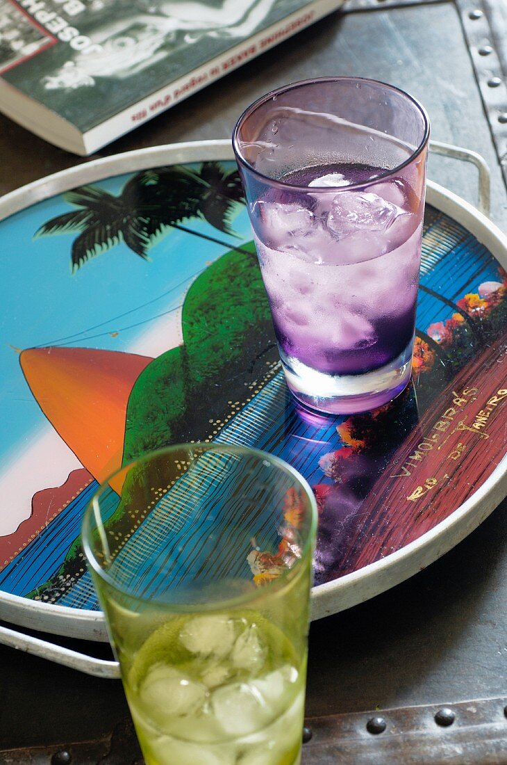 Coloured glasses of iced water on tray with picture of Sugarloaf Mountain in Rio de Janeiro, Brazil