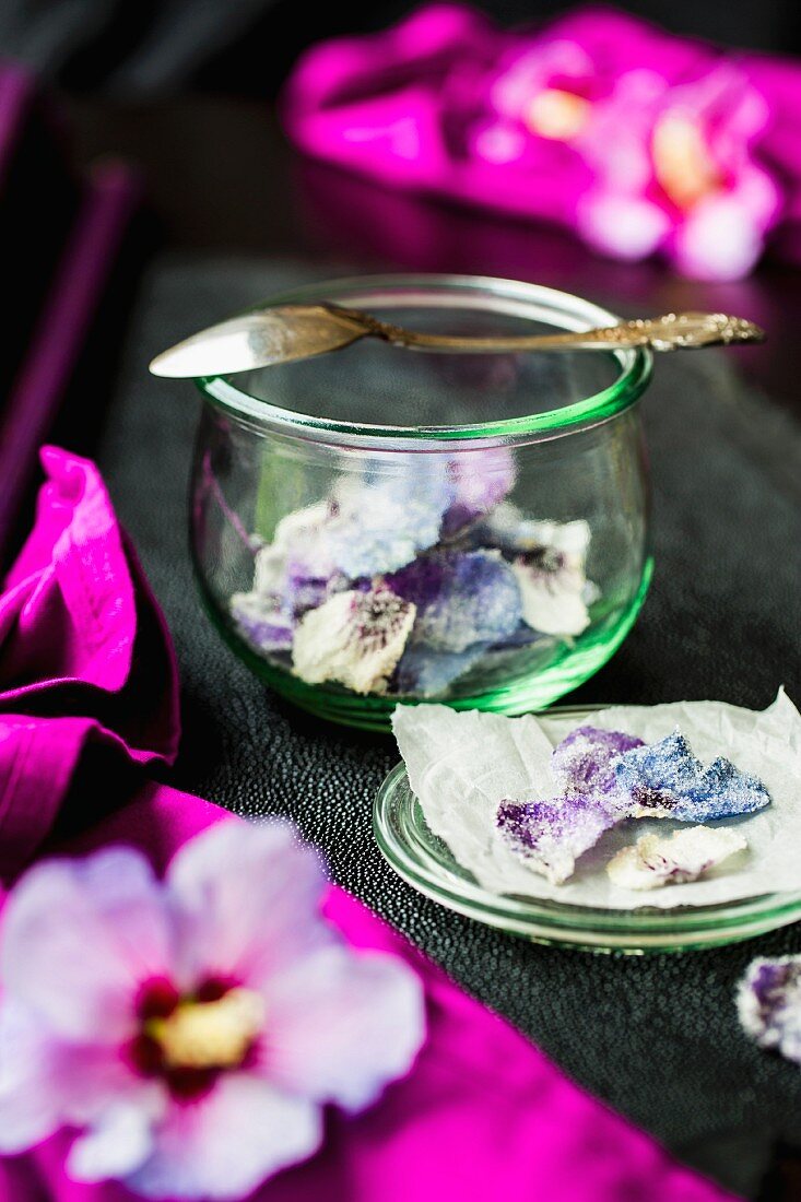Kandierte Hibiskusblütenblätter im Glas und auf Rochenleder