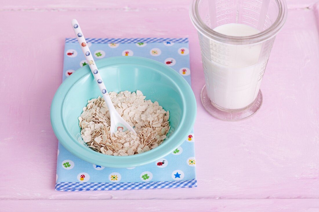 A plate of cereal grains a milk with a measuring jug