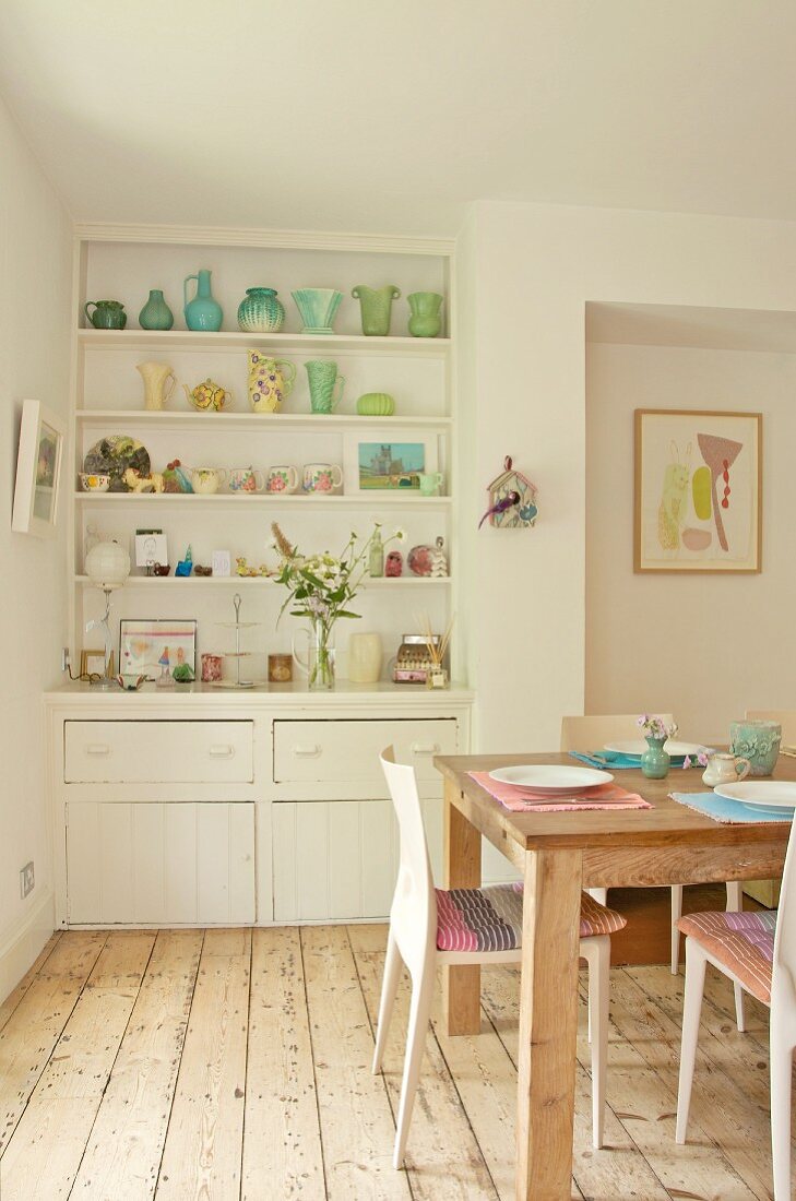 Original kitchen shelving built into niche with collection of 30s vases; wooden table and modern chairs on stripped wooden floor