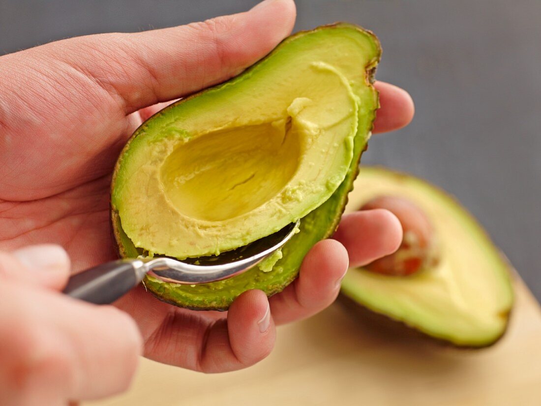 An avocado being scooped out of its skin