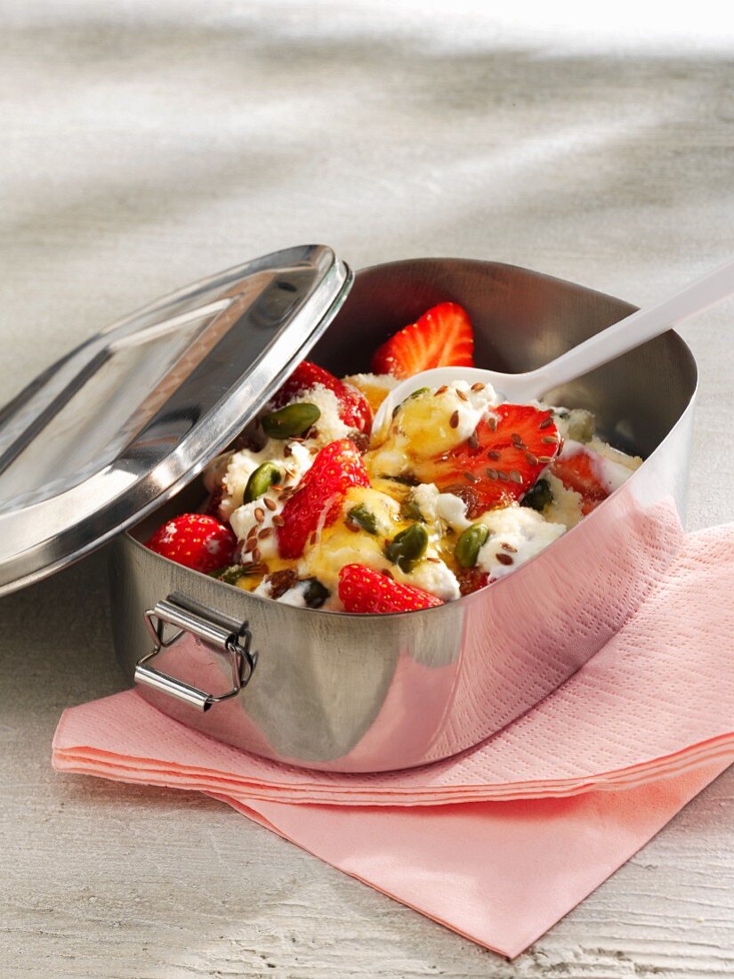 Yogurt with strawberries, pistachio nuts and breadcrumbs in a lunch box