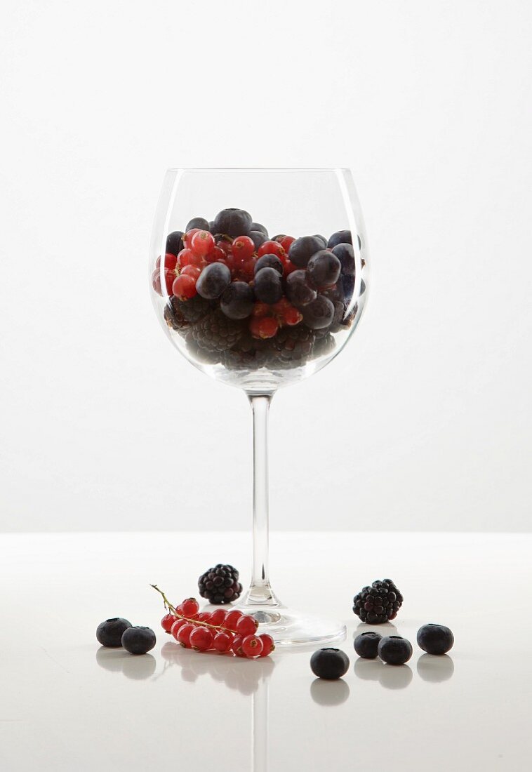 Berries in a wine glass against a white background