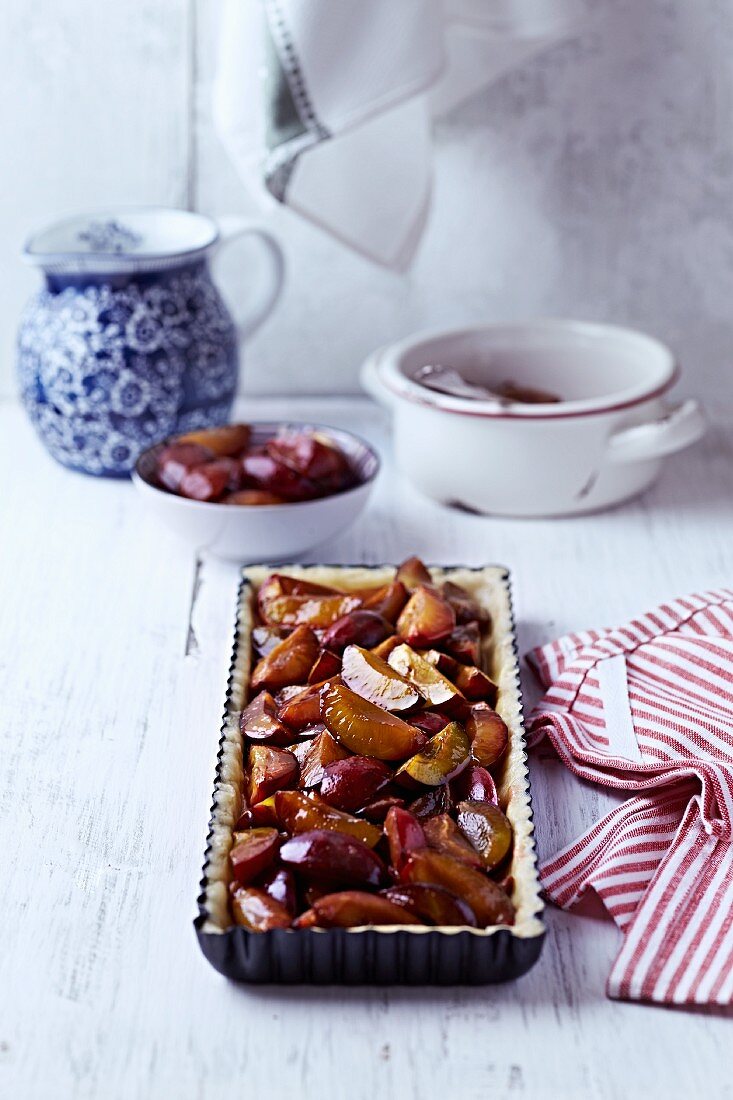 Shortcrust pastry with caramelised plums in a cake tin