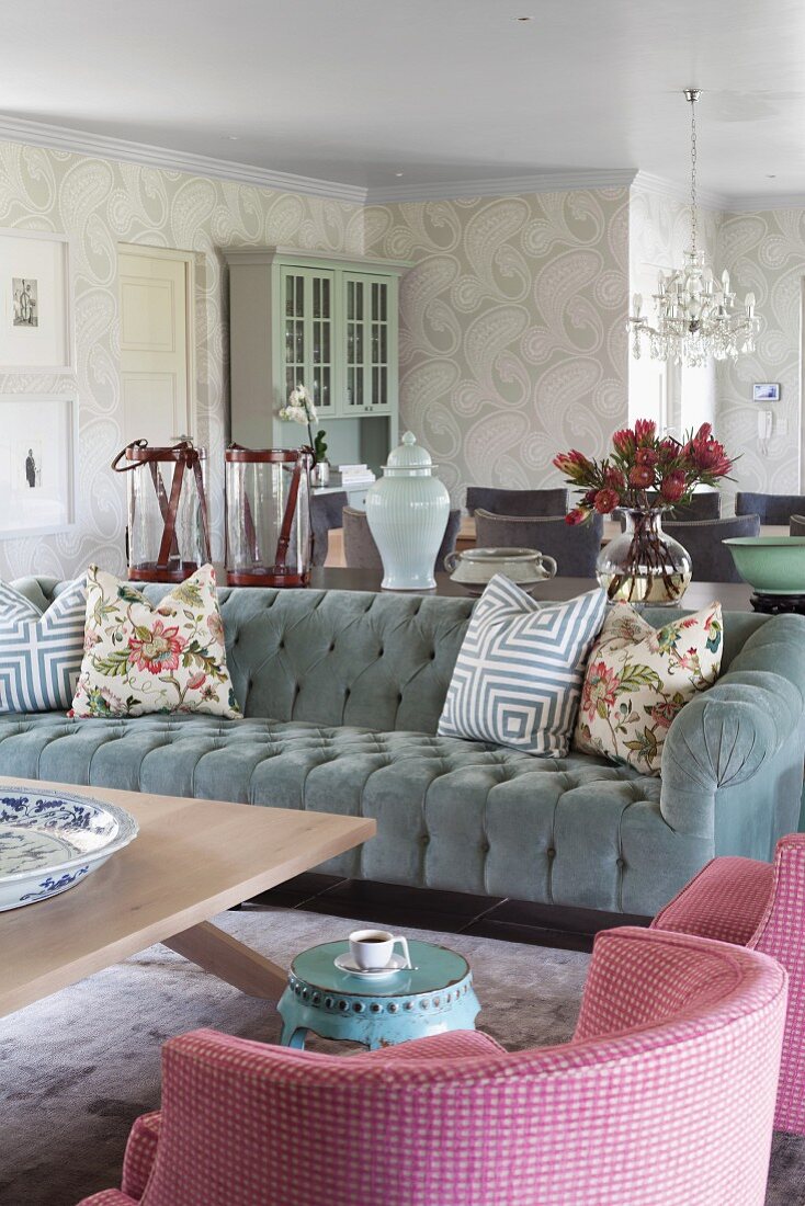 Armchair with pink and white checked cover and grey velvet sofa with scatter cushions around coffee table in romantic, elegant, country-house interior