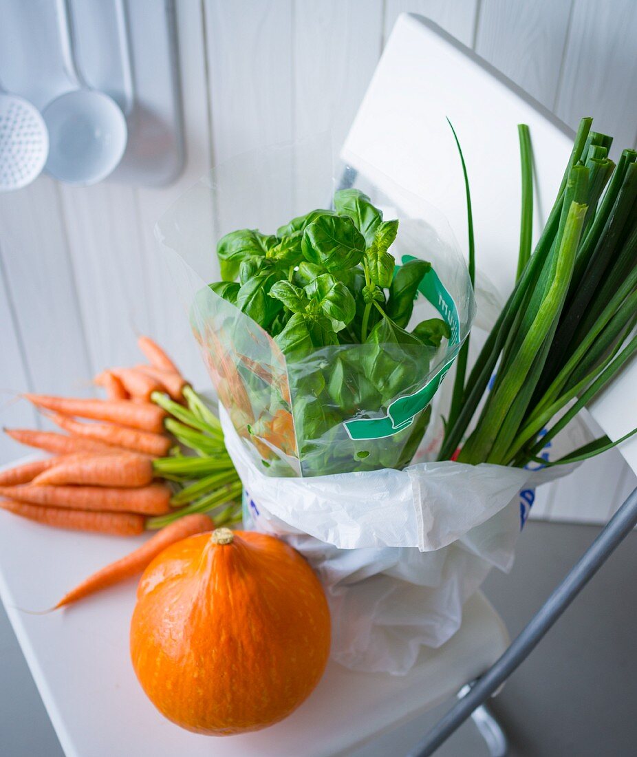 Frisches Gemüse in Einkaufstüte & auf Küchenstuhl