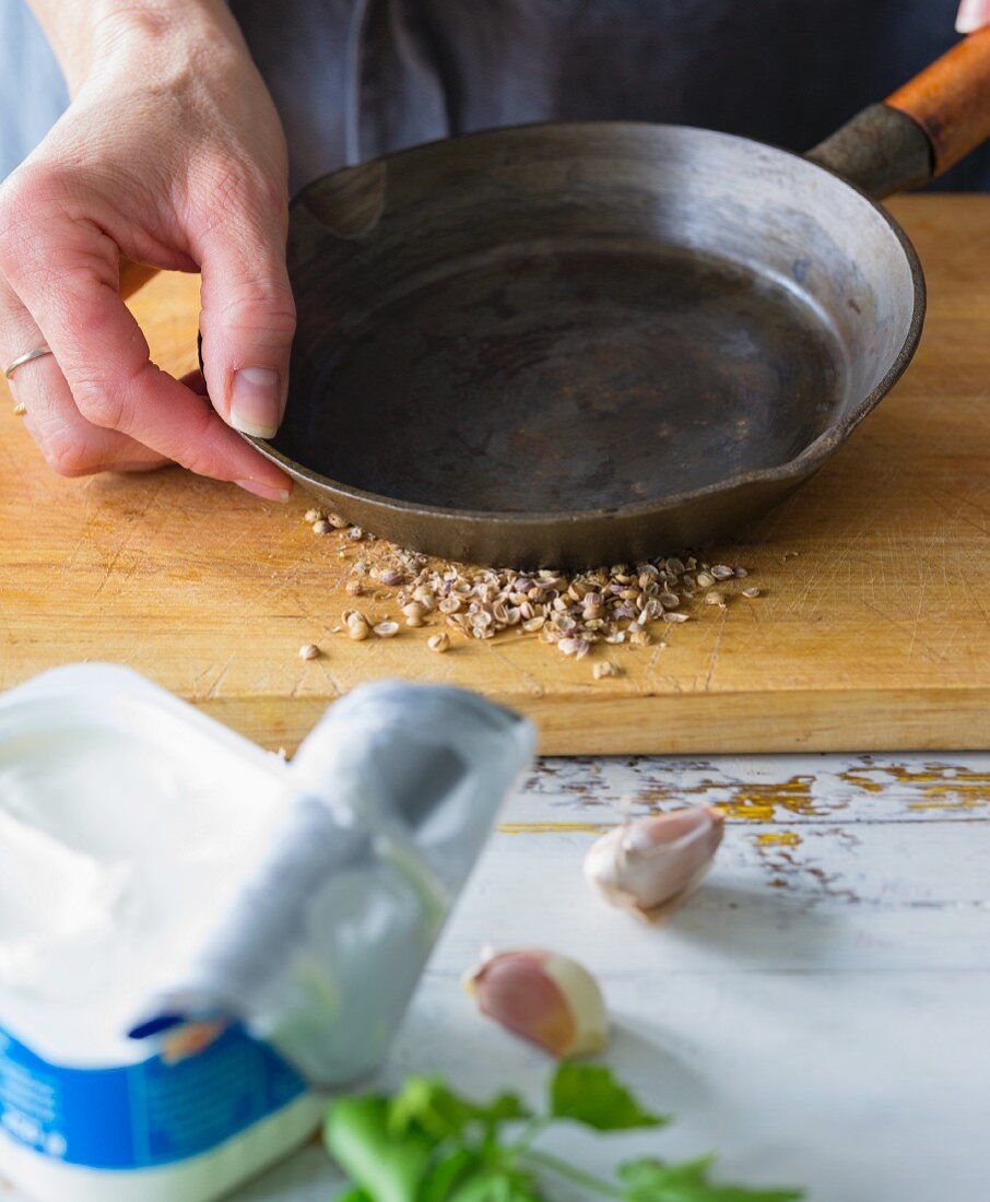 Coriander seeds being crushed with a pan