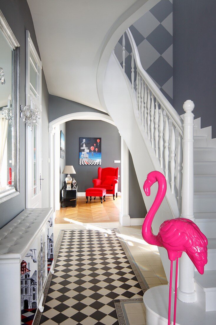 Pinkfarbene Flamingofigur am Treppenaufgang einer eleganten Eingangsdiele mit Blick in den Wohnraum