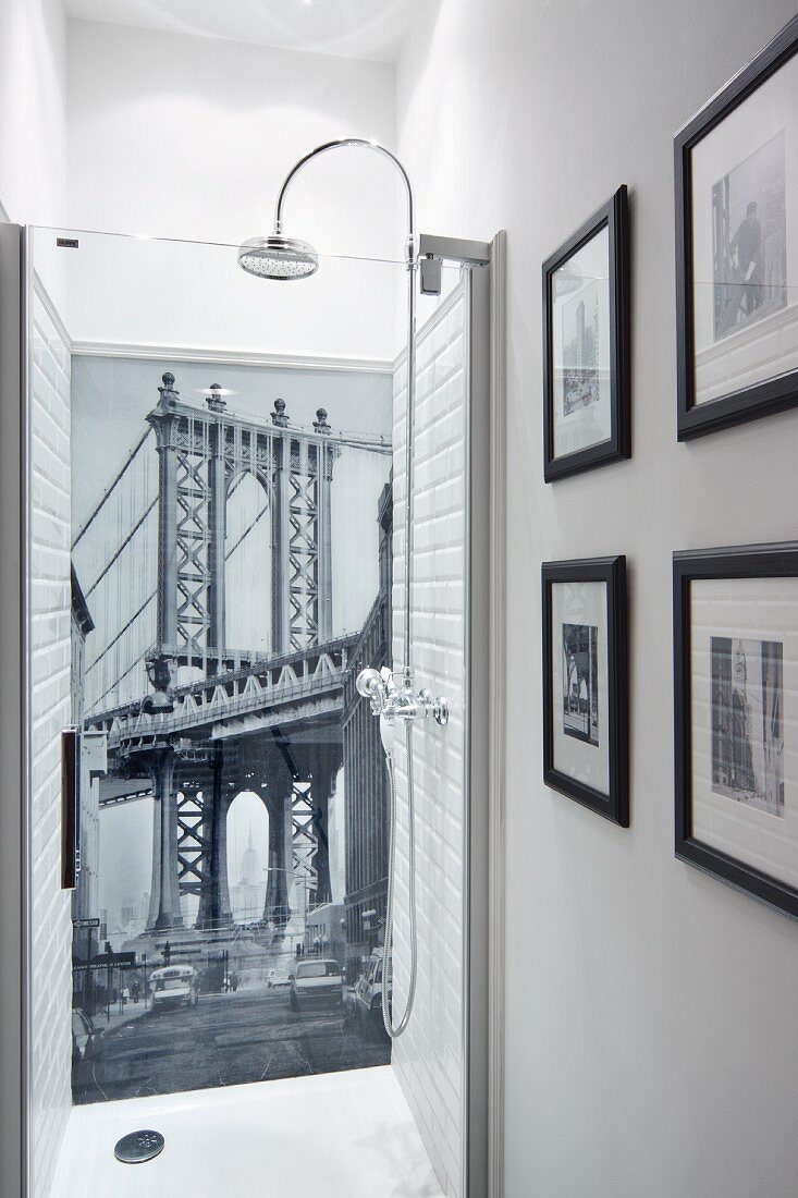Tapete mit Brückenmotiv als Rückwand in einer Dusche und gerahmte Schwarz-weiss Fotos an der Seitenwand