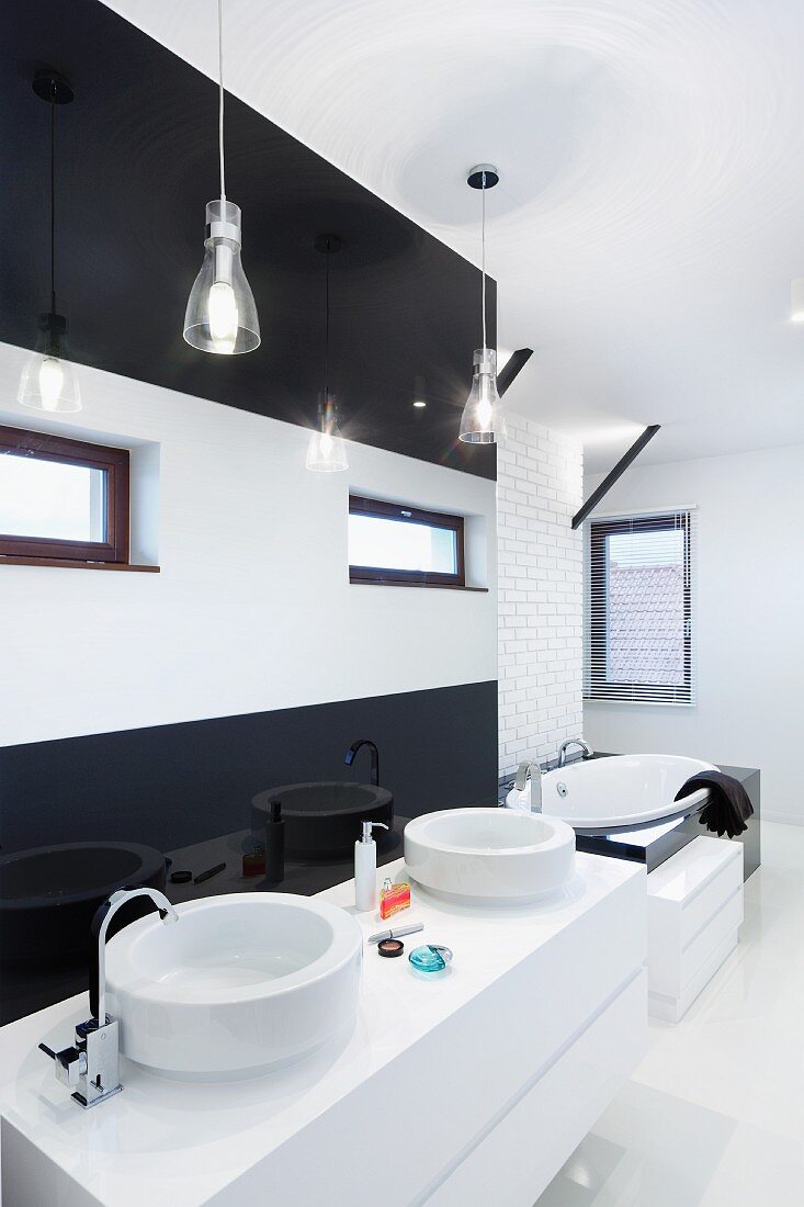 White washstand with twin basins against black and white stripes wall in designer bathroom