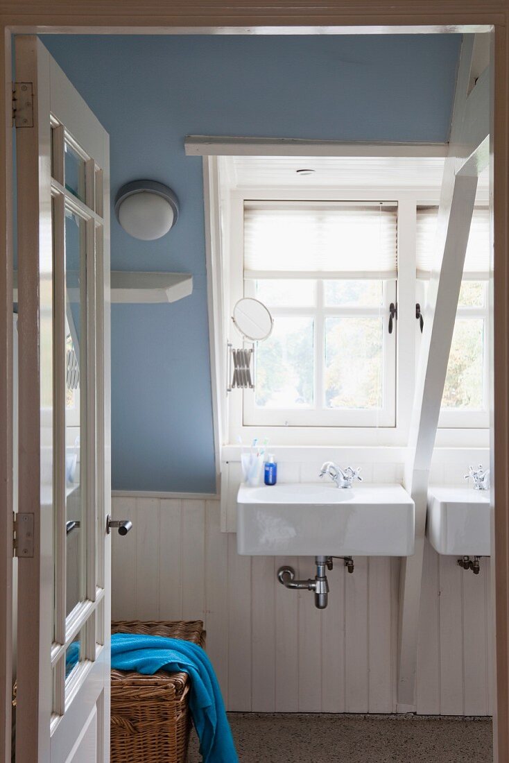 Waschbecken unter Gaubenfenster in Bad mit weiss lackiertem Holz und lavendelblau getönter Dachschräge