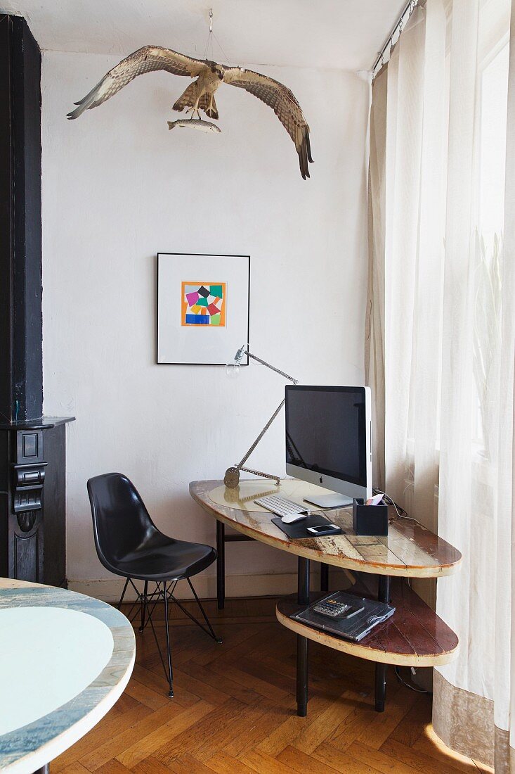 Black, classic-style shell chair at DIY computer desk below stuffed osprey