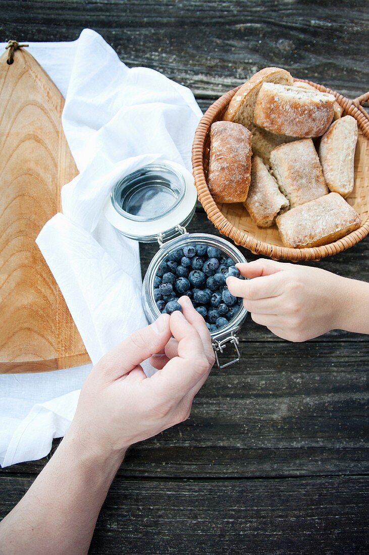 Hands taking blueberries from a jar