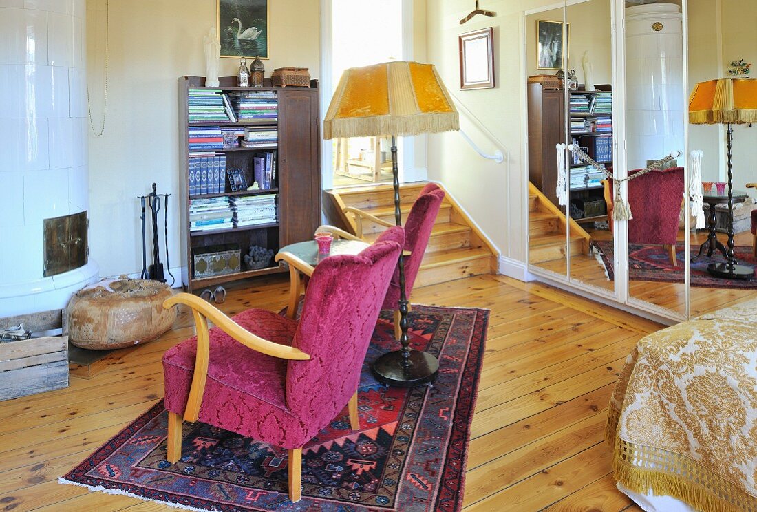 Fifties armchair, side table and standard lamp on rug in front of tiled stove