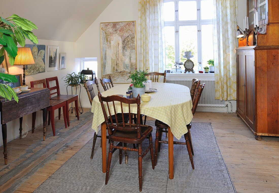 Simple, traditional dining room with sloping ceiling, antique wooden chairs and dresser