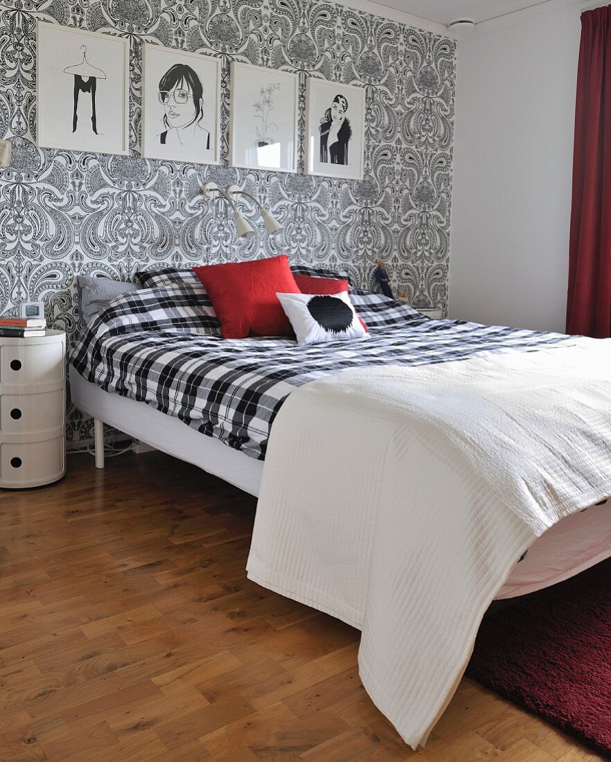 Bedroom with black and white artworks on wall with paisley wallpaper and double bed with black and white gingham bedspread