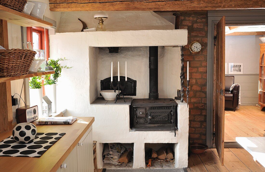 Vintage wood-fired cooker with masonry surround and firewood in niches against brick wall