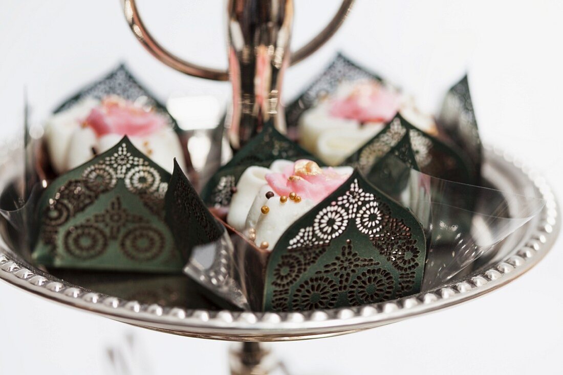 Schokoladenkonfekt in eleganter Papiermanschette mit Rosendekoration und goldenen Zuckerperlen