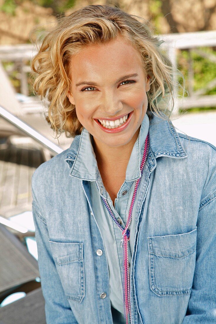 A young blonde woman outside wearing a denim skirt