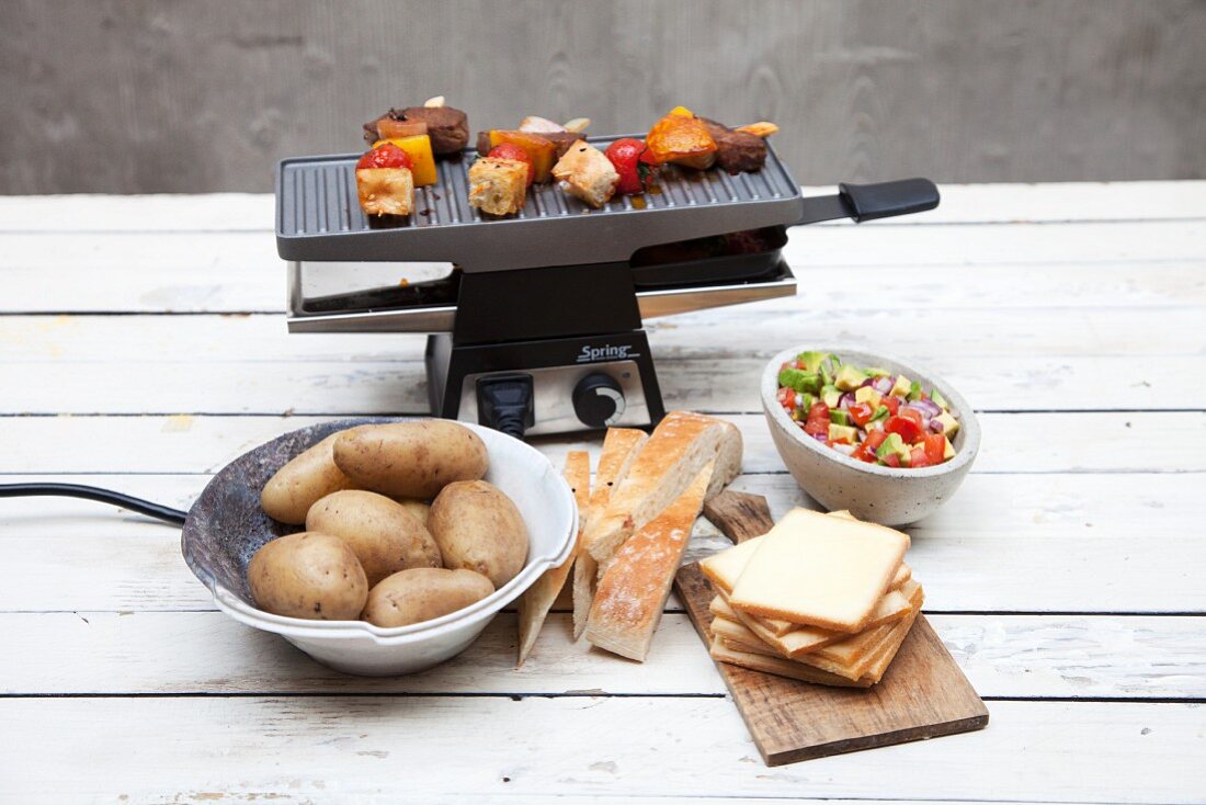 A raclette machine with ingredients in front of it